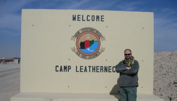 Photo of MSgt Ware in front of a very large concrete "Welcome - Camp Leatherneck" sign