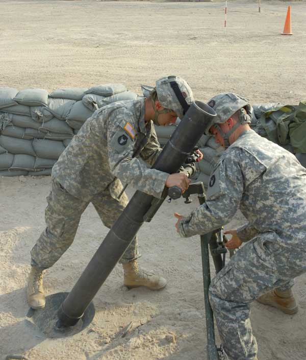 Two uniformed US Army soldiers at a mortar tube during a drill at Camp Fallujah, Iraq
