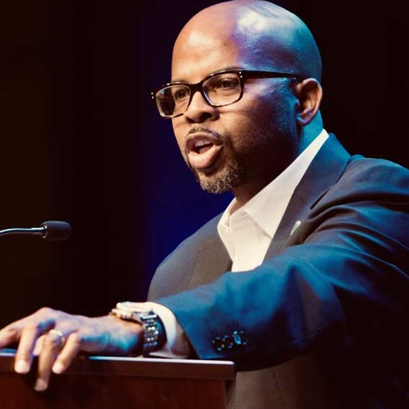 Sherman Gillums Jr. speaking into a podium microphone