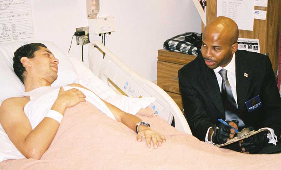 Sherman Gillums Jr. visiting a patient in a hospital bed