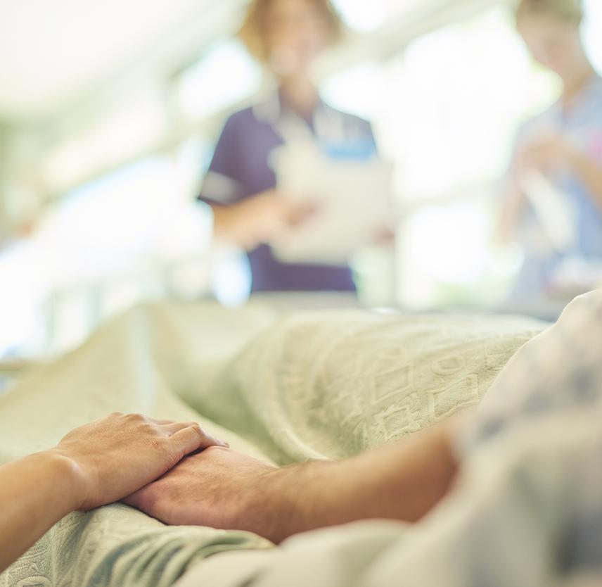 Blurred image of a patient on a hospital bed surrounded by staff