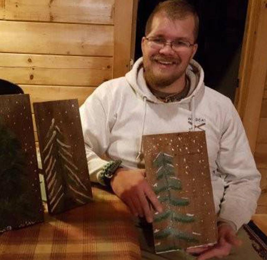Taylor Bingaman with plaques showing pine tree carvings