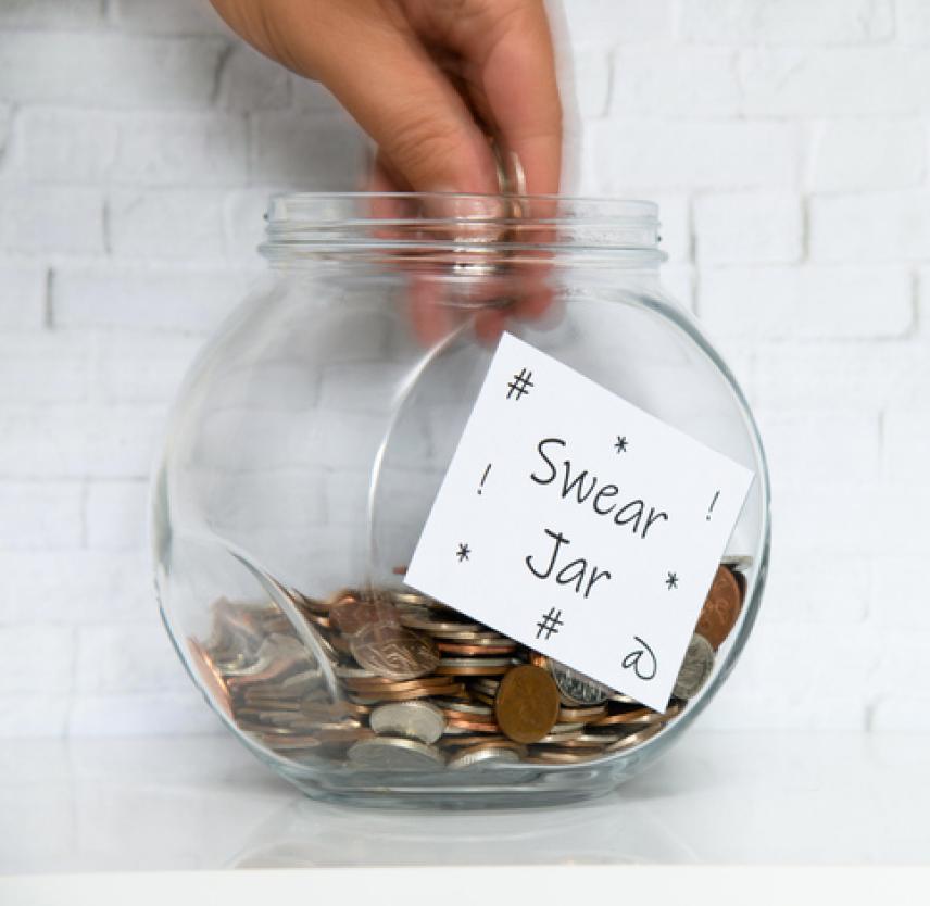 A hand places coins in a swear jar