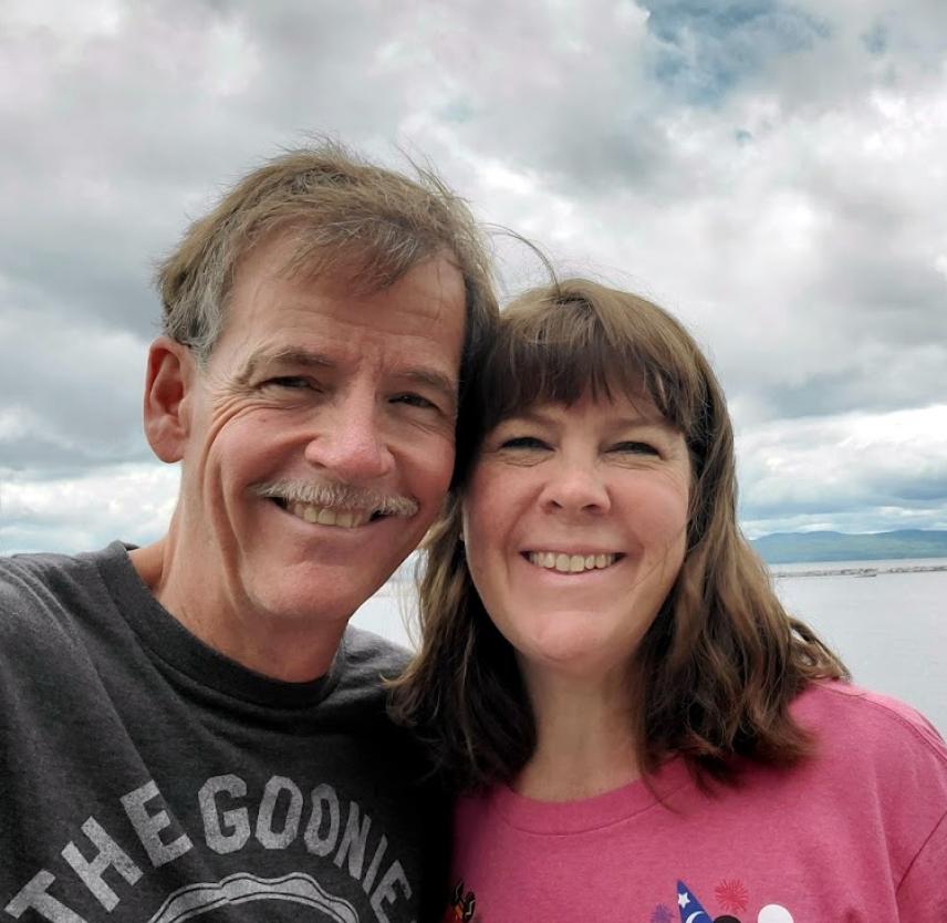 David Grant: Mental Health Challenges After Brain Injury David Grant and his wife smiling in front of a cloudy sky over a body of water