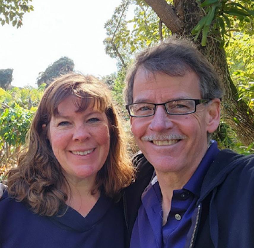 David and his wife smiling surrounded by foliage
