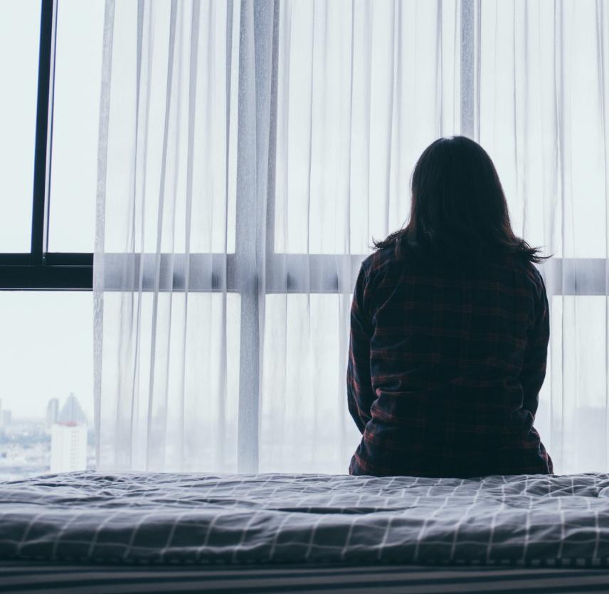 A woman sits alone on a bed