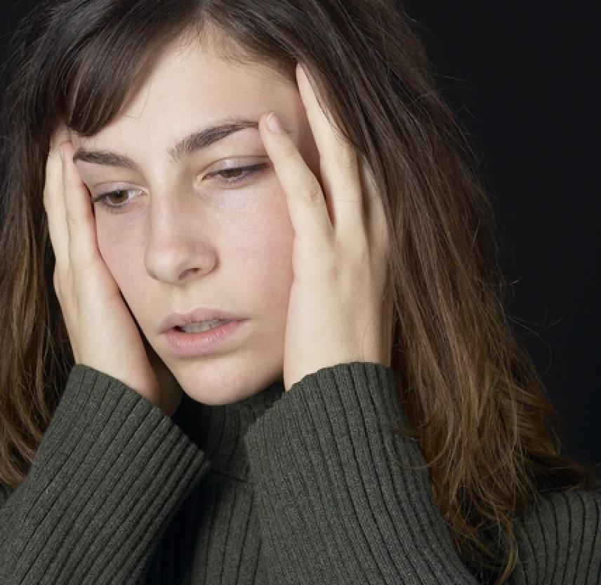 Woman holding her head in her hands with a pained look on her face