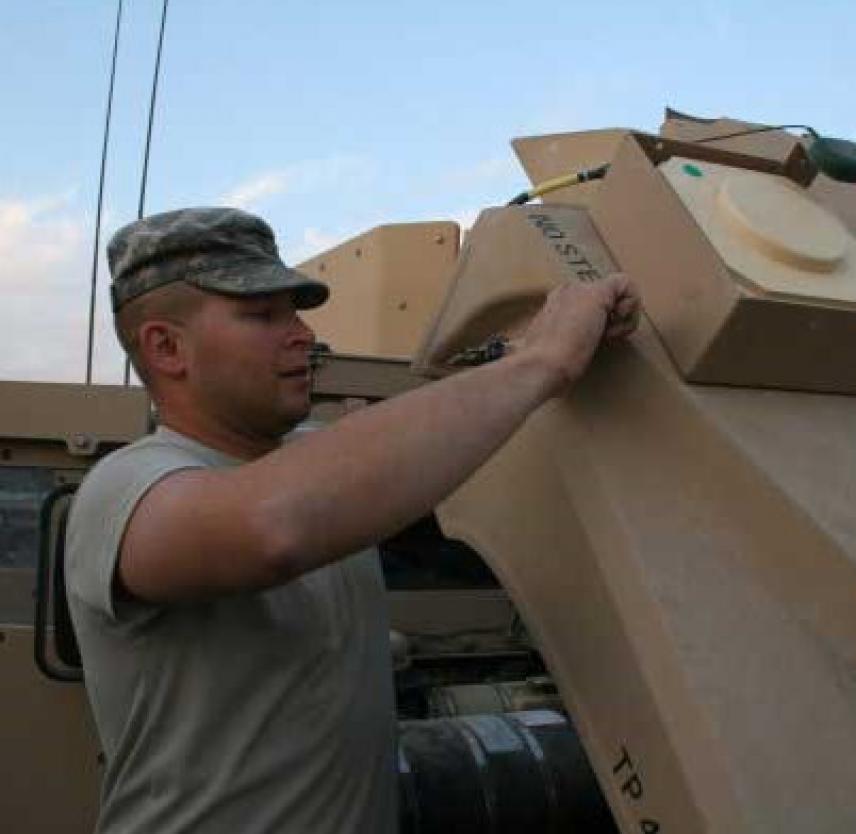 Tom Smoot upgrades HMMWV GPS transceivers in Iraq’s Diyala Province in December 2006. Photo courtesy of the author. Photo of a United States Army soldier adjusting equipment on a Humvee - Tom Smoot upgrades HMMWV GPS transceivers in Iraq’s Diyala Province