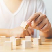 Hand moving small wooden cube blocks to put them in a pattern