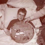 Adam posing with his birthday cake in a hospital bed