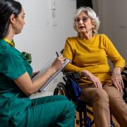 A young female doctor speaks to an eldery woman in a wheelchair