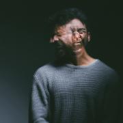 Studio shot of a young man experiencing mental anguish and screaming against a black background