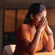 A woman cradles her head in her hands, exhausted