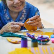 An elderly woman working on needle crafts.