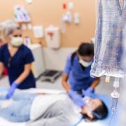 Two nurses attend to a patient laying in a hospital bed