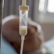 A feeding tube drips for a patient in a coma