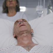 Patient with breathing tube on a gurney visibly in pain