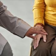 close up of two senior women holding hands in a support group