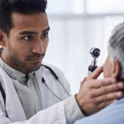 A young male doctor gives an elderly woman an eye exam