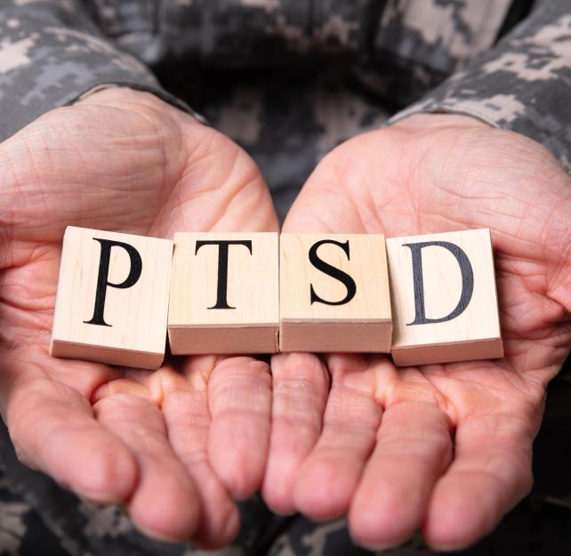 Man holding tiles that spell PTSD in his palms