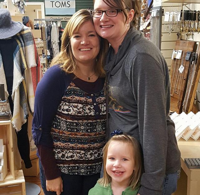 Nicole standing with fellow caregiver Danielle and young girl. All of them are smiling.