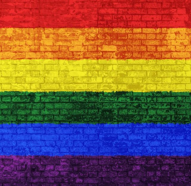 A rainbow Gay Pride flag painted on a brick wall