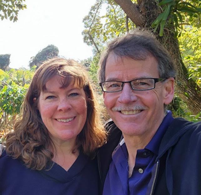 David and his wife smiling surrounded by foliage