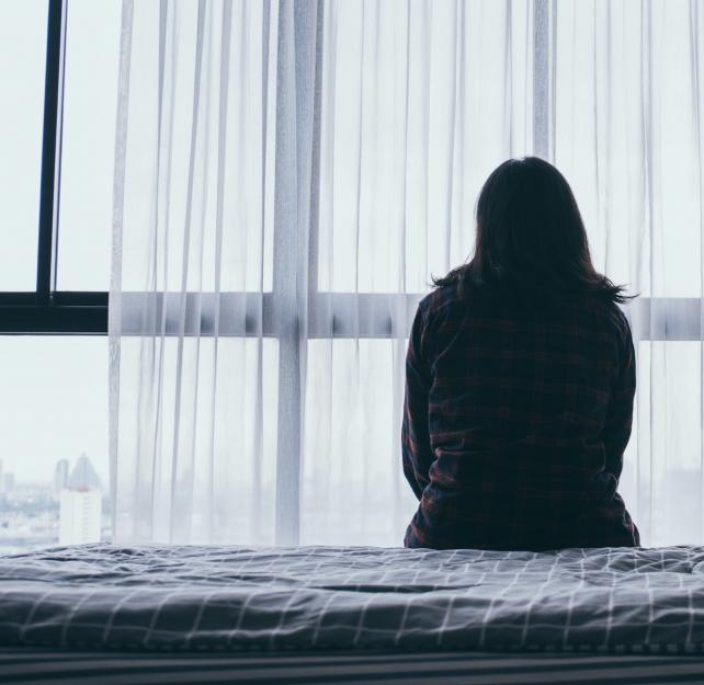 A woman sits alone on a bed
