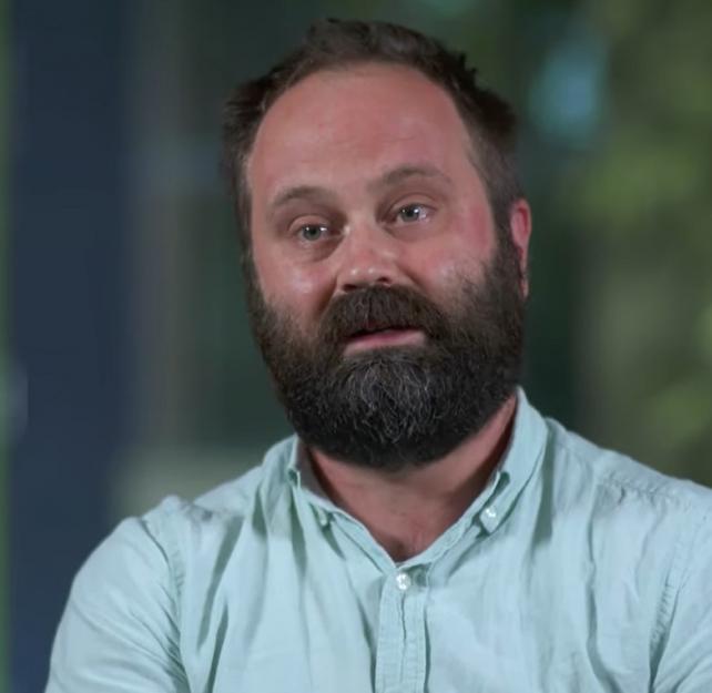 Dr. Brian Klassen in a light but button down shirt in front of an out-of-focus green background