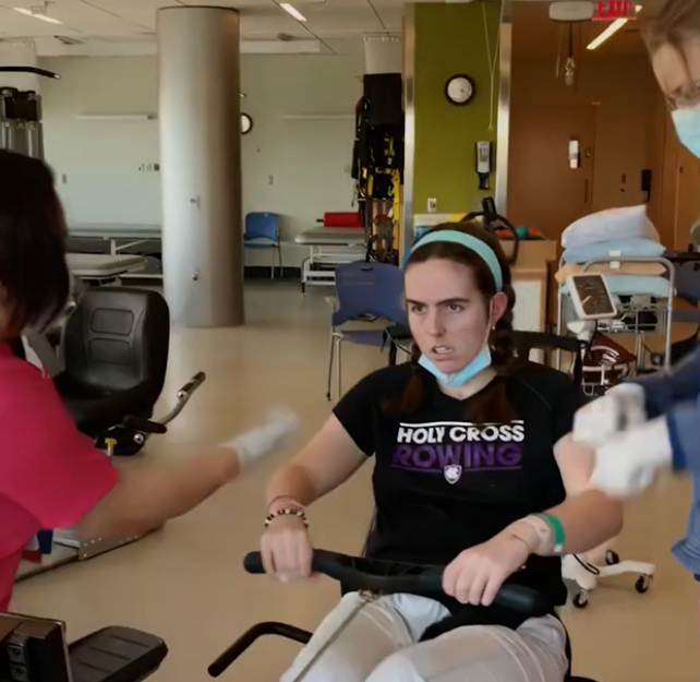 A person doing physical therapy with two staff.