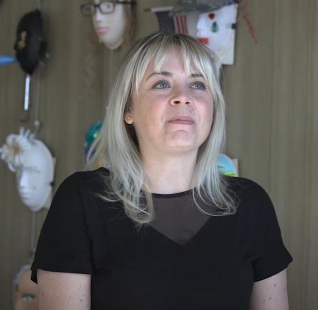 Art Therapist Stephanie Clark sitting in front of a wall of masks