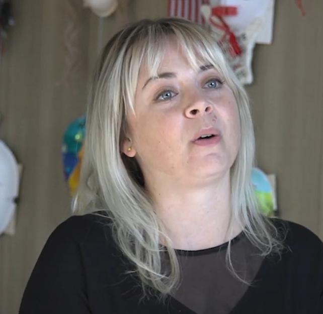Art Therapist Stephanie Clark sitting in front of a wall of masks