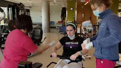 A person doing physical therapy with two staff.