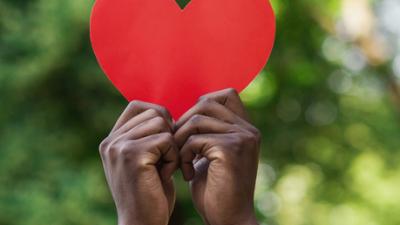 Two hands holding a paper heart