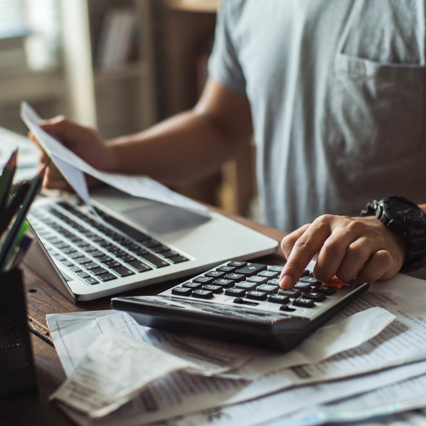 Man using a calculator holding financial paperwork at a desk