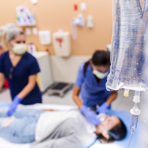 Two nurses attend to a patient laying in a hospital bed